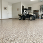 Garage with a golf cart on a speckled epoxy flake floor, tools, and bicycles in the background.
