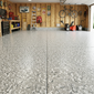 Garage with a textured concrete epoxy floor, tools, and equipment on wooden walls.