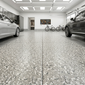 Garage epoxy floor interior with two cars, bicycles, and a wall art piece.